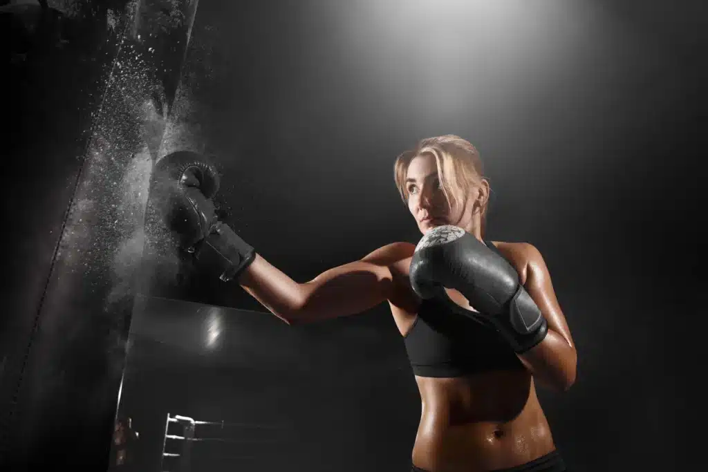 femme qui frappe dans un sac de frappe en cours de boxe